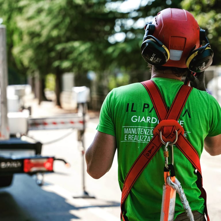 Worker in green safety vest and red hard hat with harness standing at an outdoor construction site